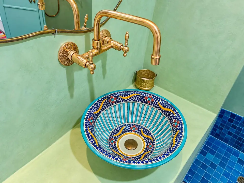 A hand-painted ceramic basin and brass tap in green tadelakt