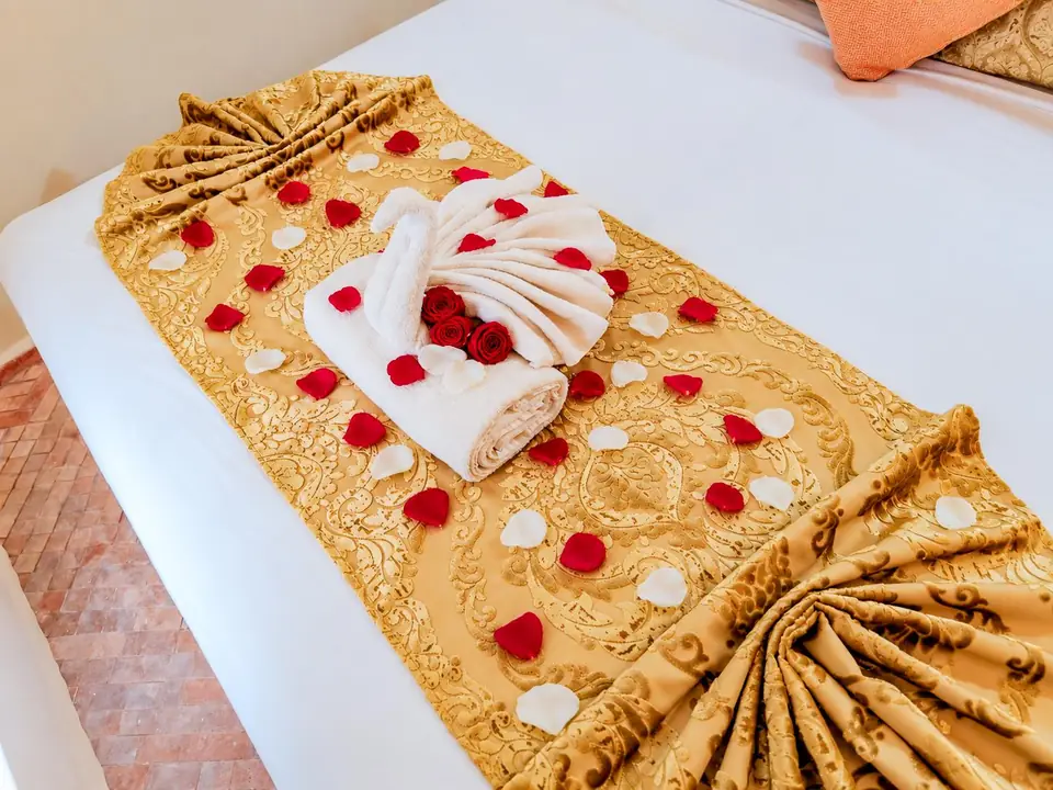 A turndown with towel swans and rose petals on a gold runner