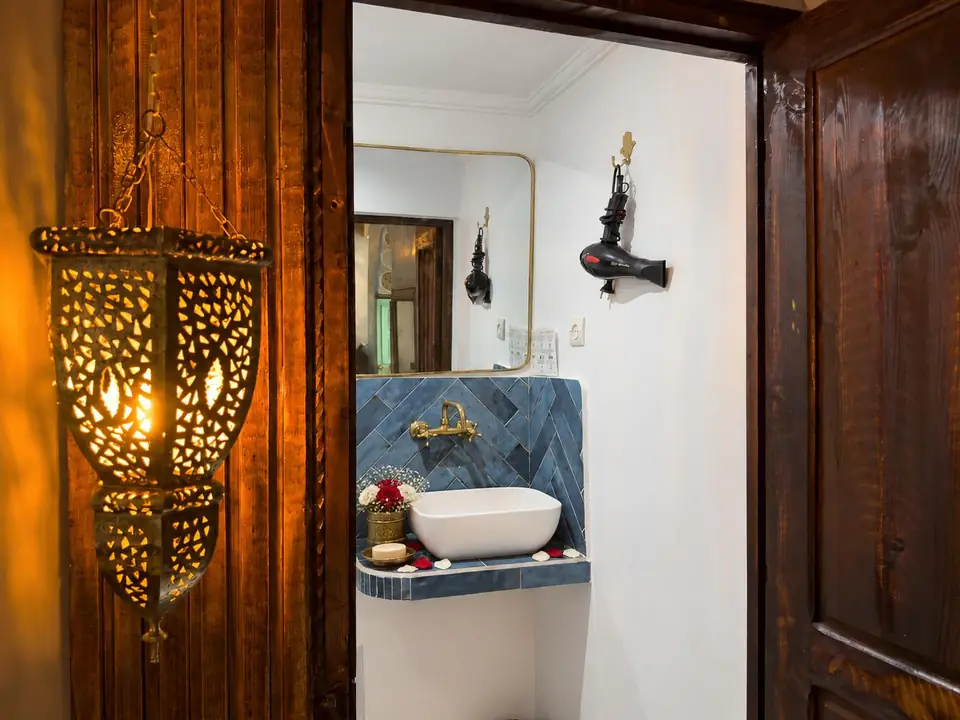 A pierced brass lantern beside a tiled washbasin