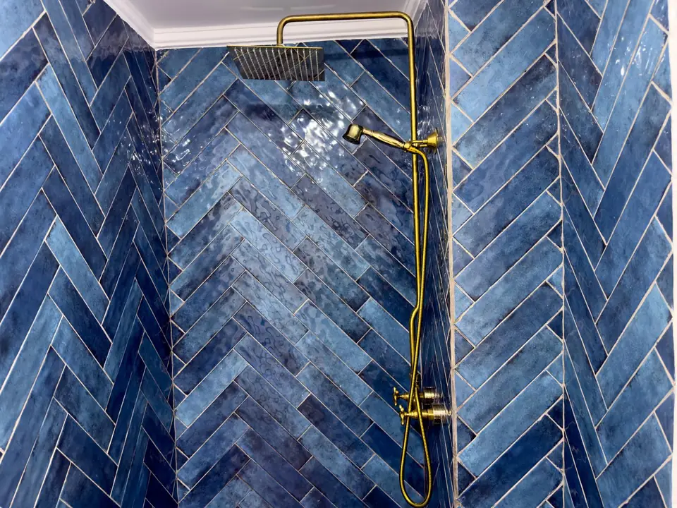 Indigo herringbone tiles and a brass rain shower