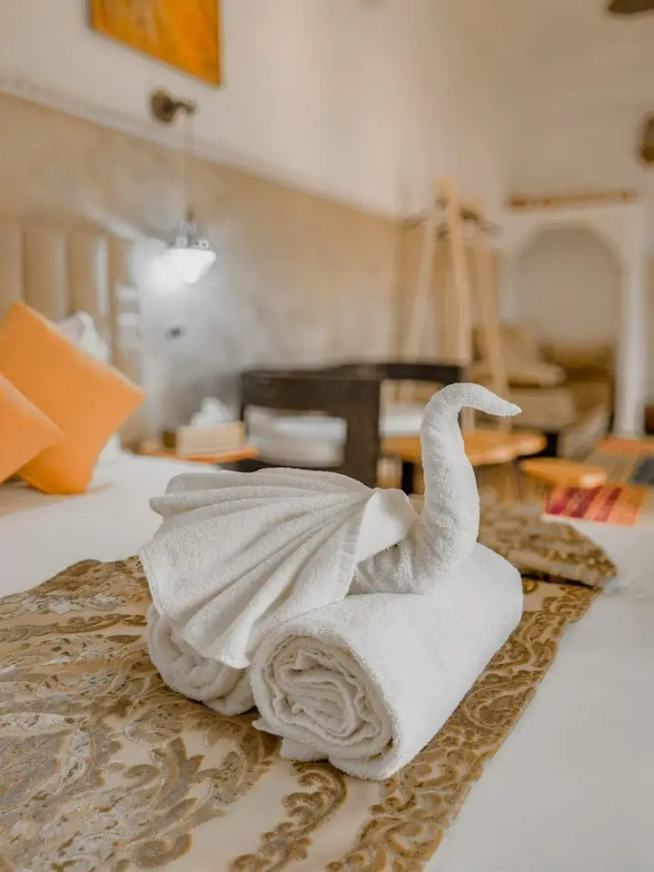 A towel folded into a swan on a gold runner